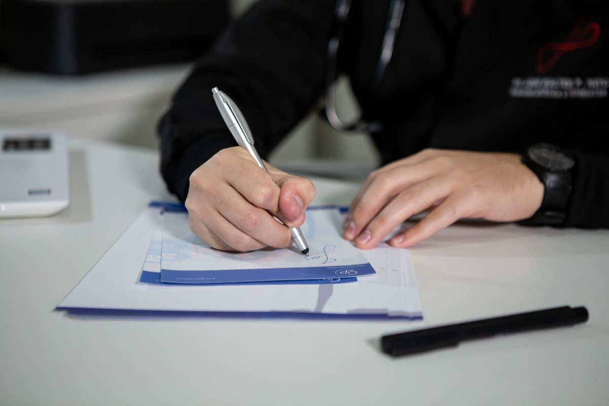 Une main remplit une feuille de soins au stylo sur un bureau